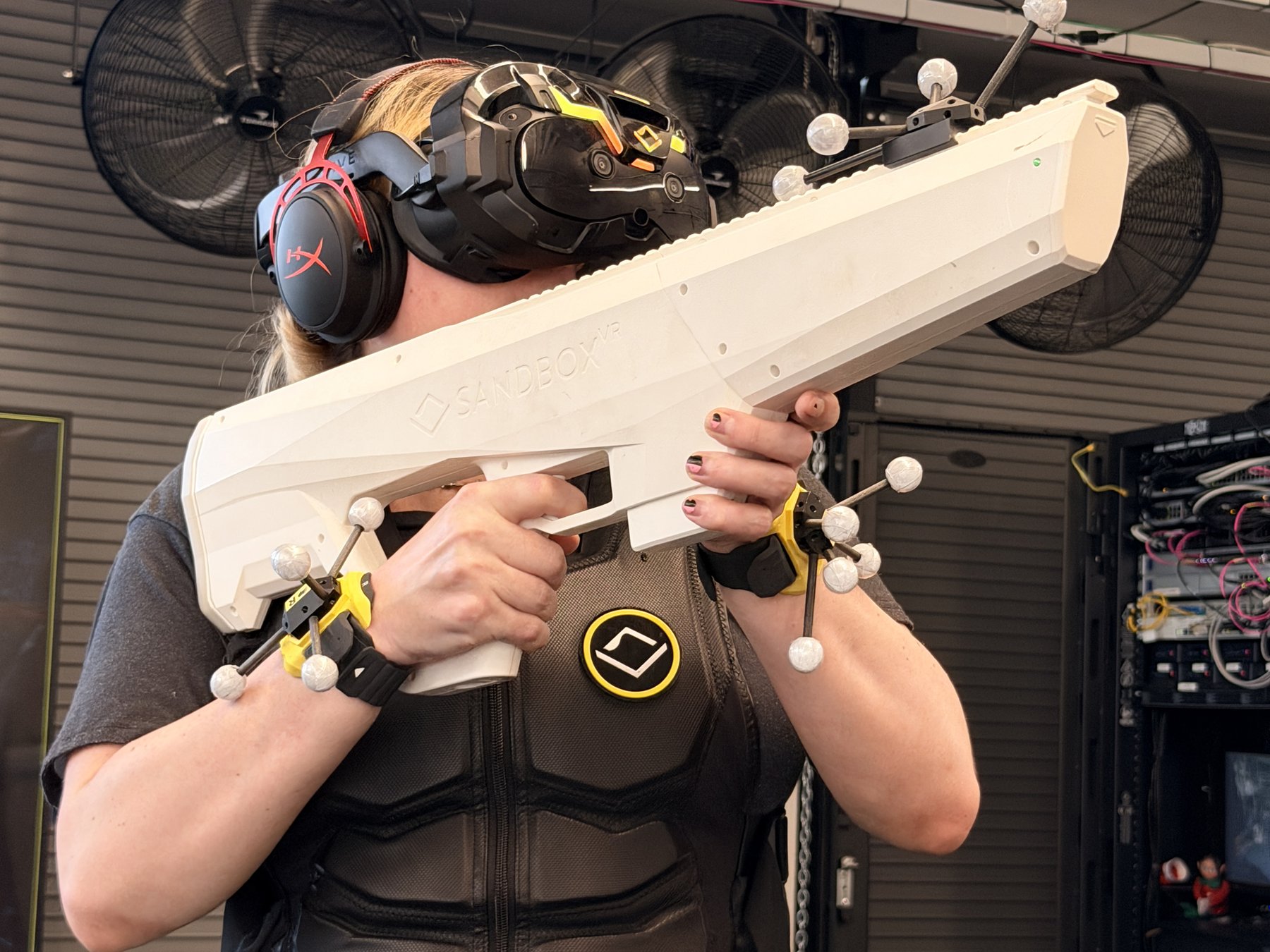 Player shouldering a rifle prop with wrist trackers fitted