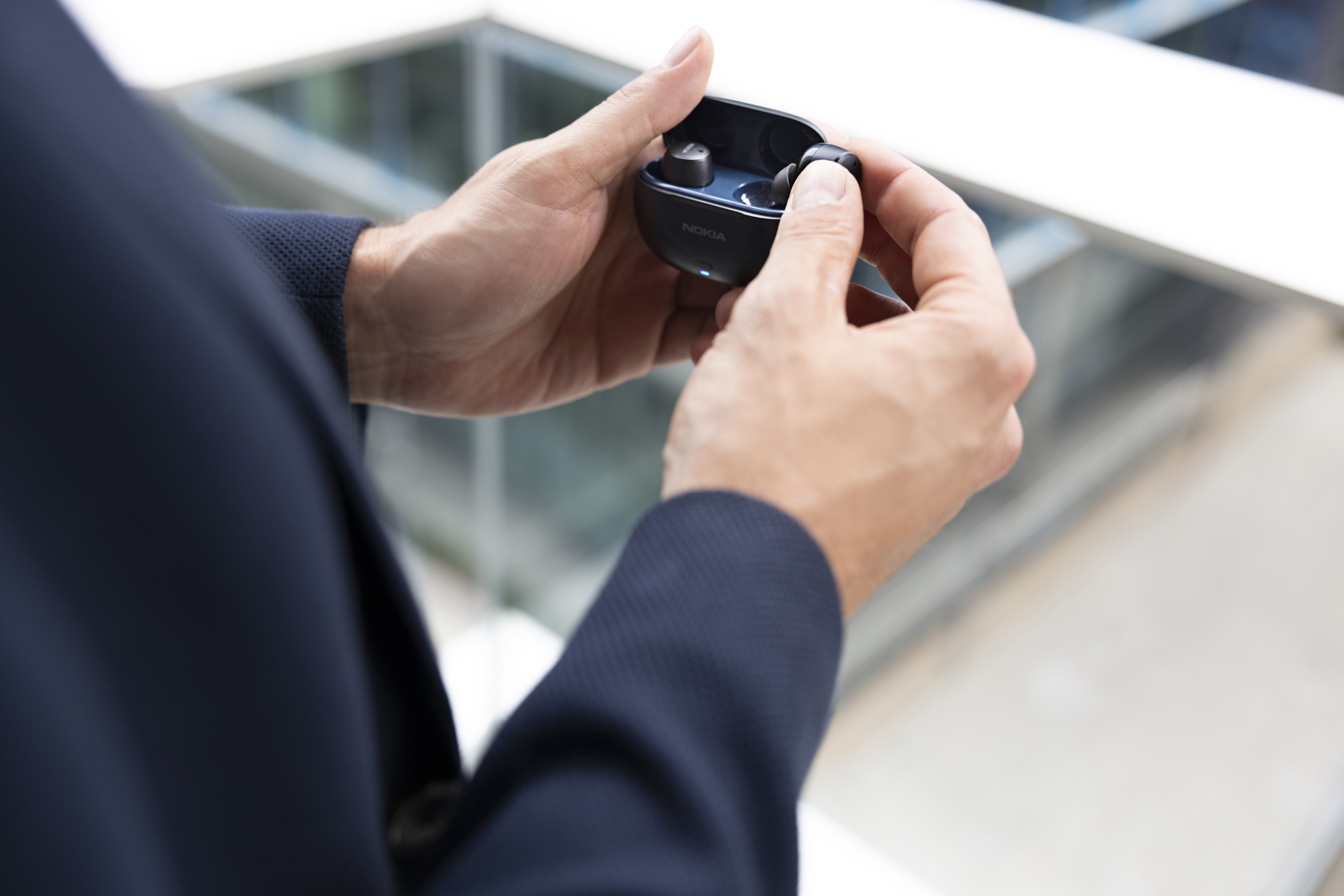 Professional wearing Nokia earbuds on a city balcony